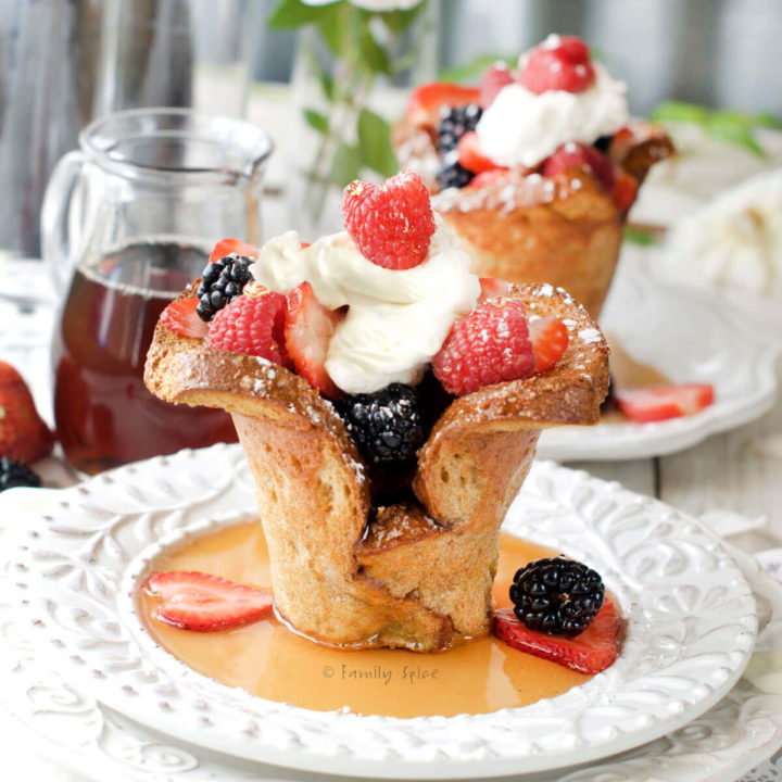 Side view of baked french toast cups filled with berries and whipped cream