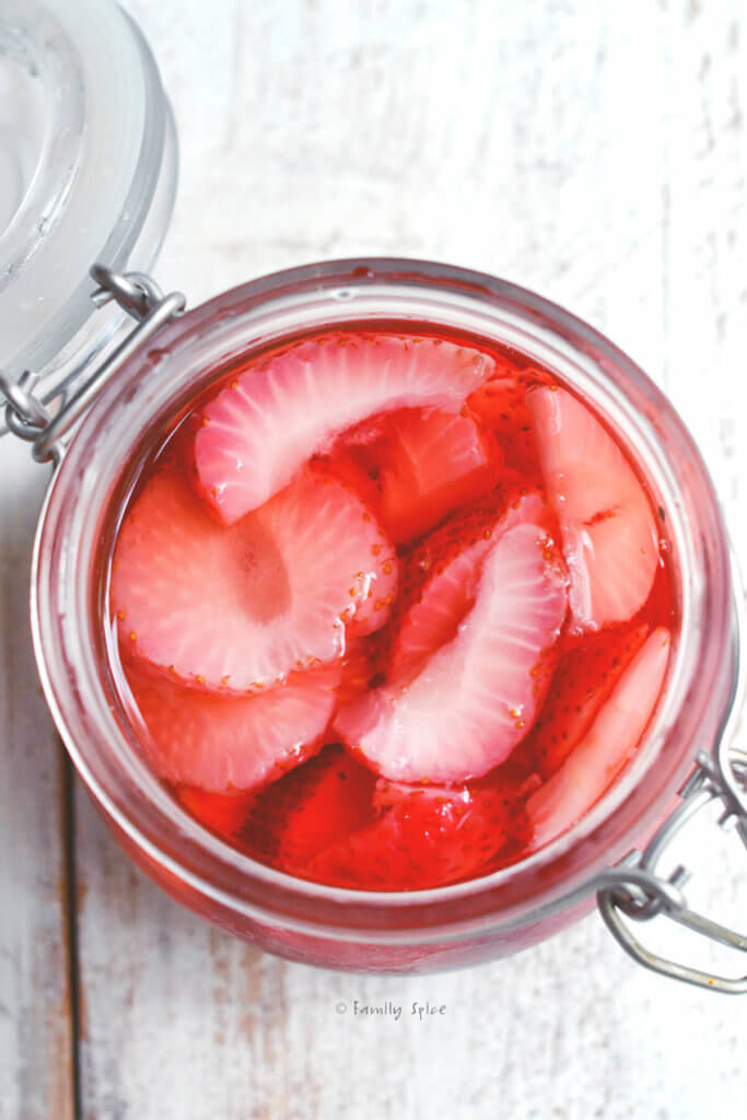 Top view of strawberry slices infused in vodka in a mason jar