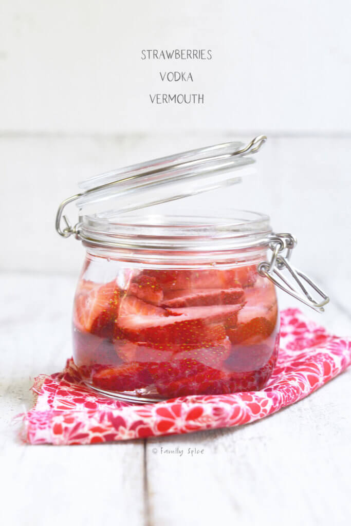 Side view of strawberry slices infused in vodka in a mason jar
