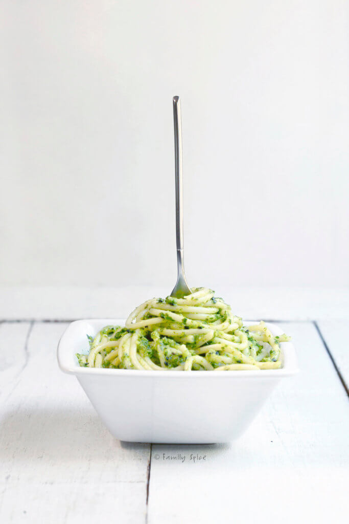 A bowl of spaghetti with bok choy pesto with a fork in it