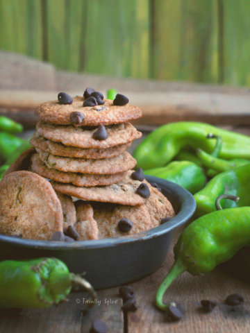 A stack of chocolate chip cookies made with and surrounded by green Hatch chiles
