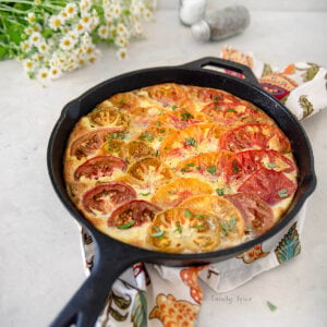 A freshly baked tomato frittata with flowers around it.