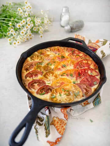 A freshly baked tomato frittata with flowers around it.