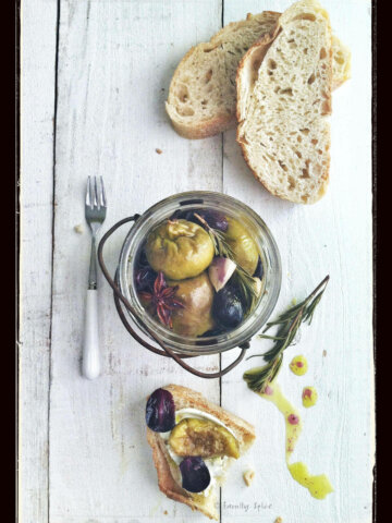 Top view of a jar of figs poached in olive oil with slices of bread with a grunge filter
