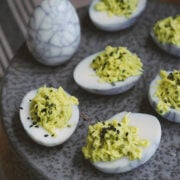 Closeup of halloween deviled eggs made with green filling and web design on the whites