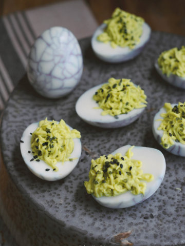 Closeup of halloween deviled eggs made with green filling and web design on the whites
