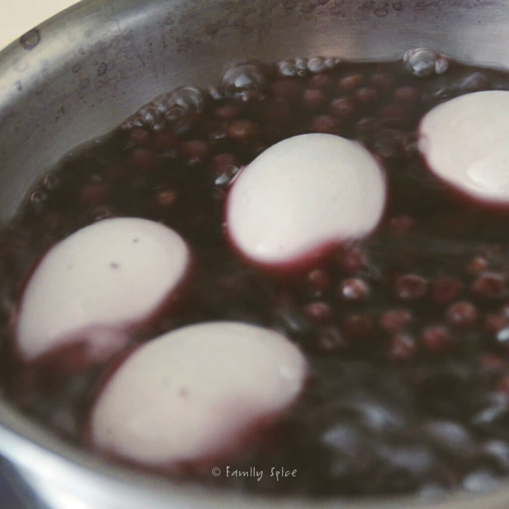 Making hard boiled eggs in small pot with bubbling blueberries