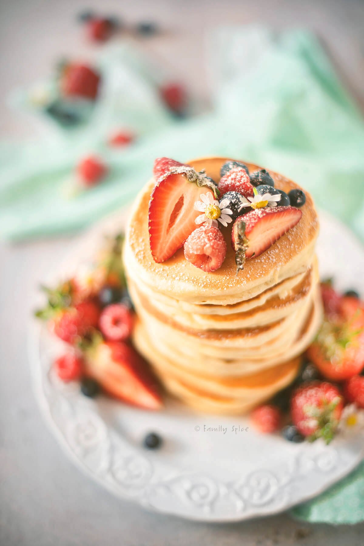 Top view of a stack of yogurt pancakes topped and surrounded with fresh berries