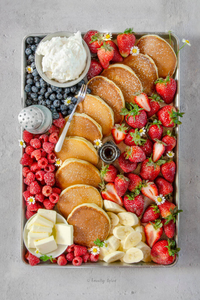 A yogurt pancake charcuterie board with assorted fruits and toppings