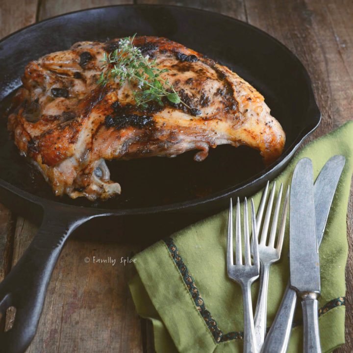 Roasted turkey breast in a cast iron pan with a green napkin and utensils