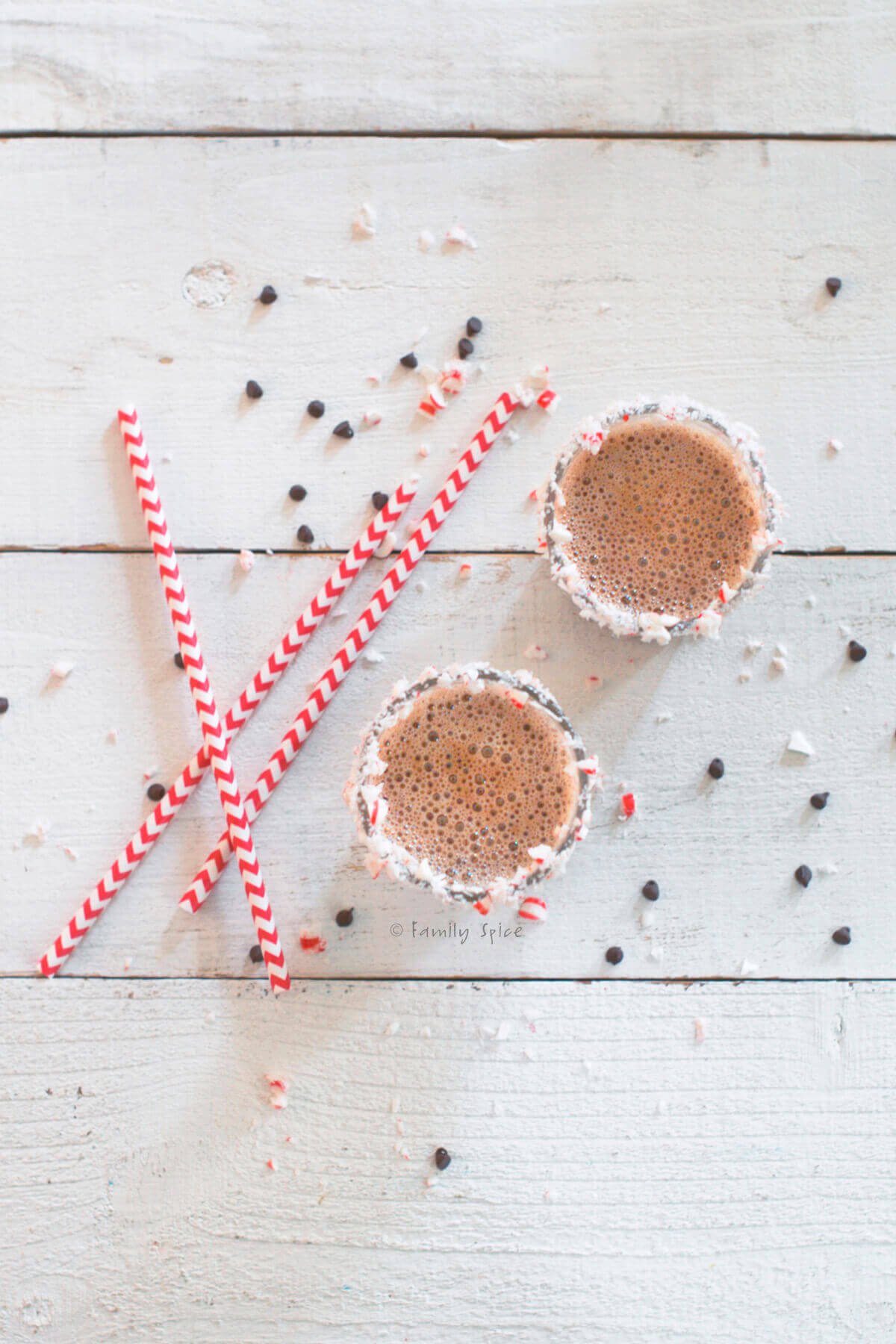 Top view of two glasses of chocolate eggnog with crushed peppermint along the glass rim.
