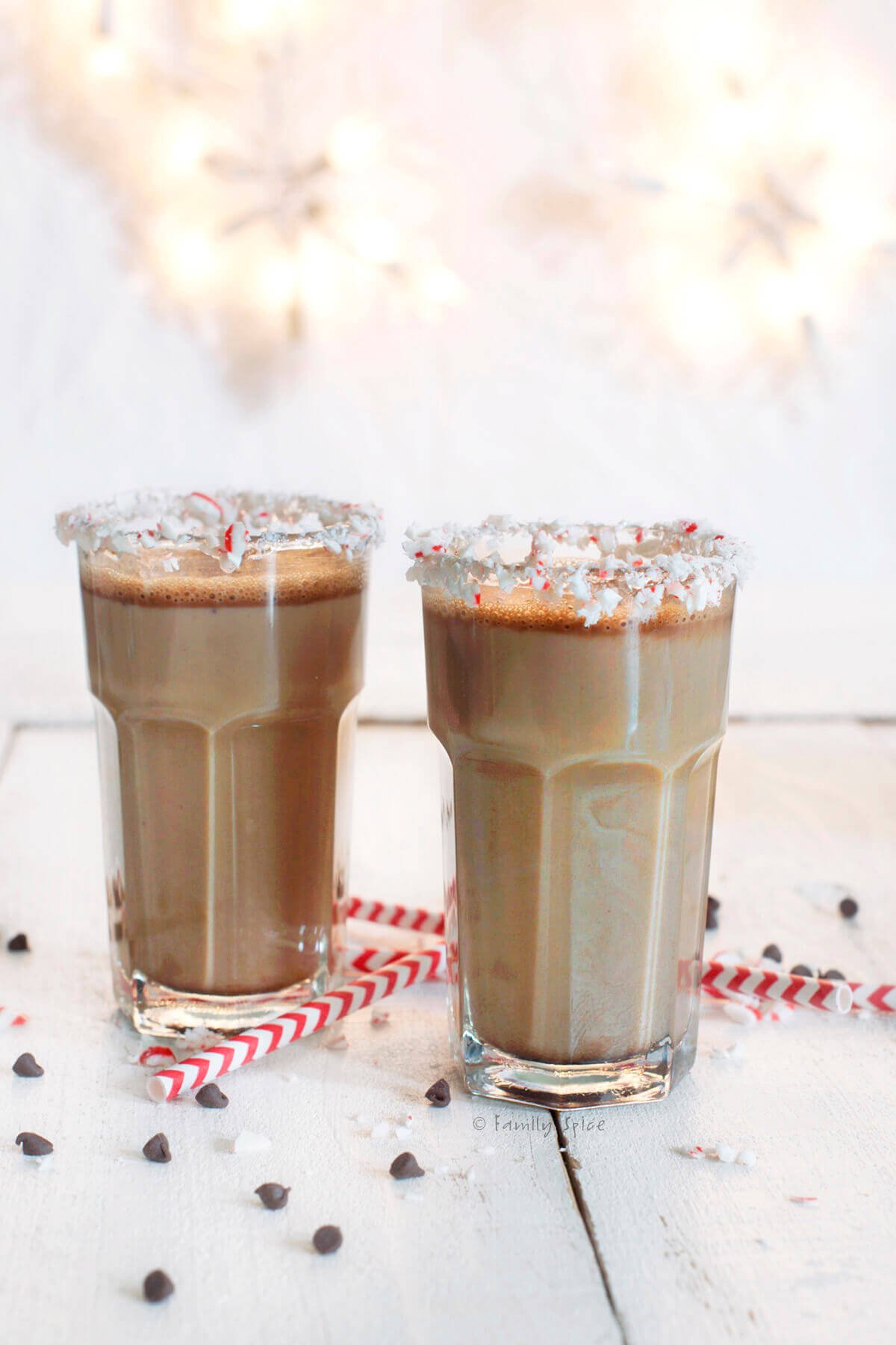 Closeup of two glasses of chocolate eggnog with crushed peppermint along the glass rim.