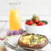 Side view of a portobello keto quiche in a cast iron pan with a carafe of orange juice and bowl of strawberries behind it