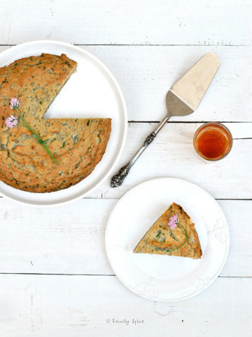 Overhead view of Persian Mashed Potato Quiche with herbs on a serving plate with a piece cut out (Kookooyeh Sib Zamini)