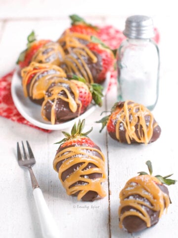 Side view of a white plate with chocolate and caramel covered strawberries.