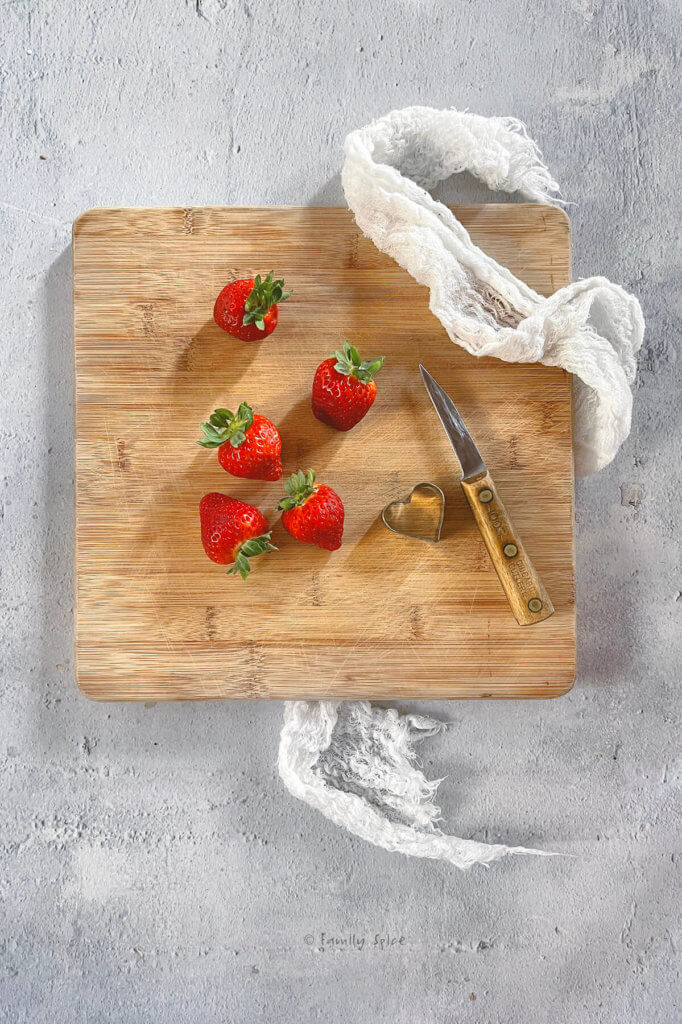 Strawberries with a small knife of a wood cutting board