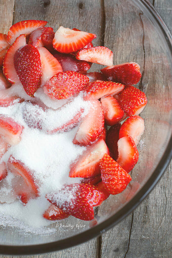 A bowl full of chopped strawberries with sugar by FamilySpice.com