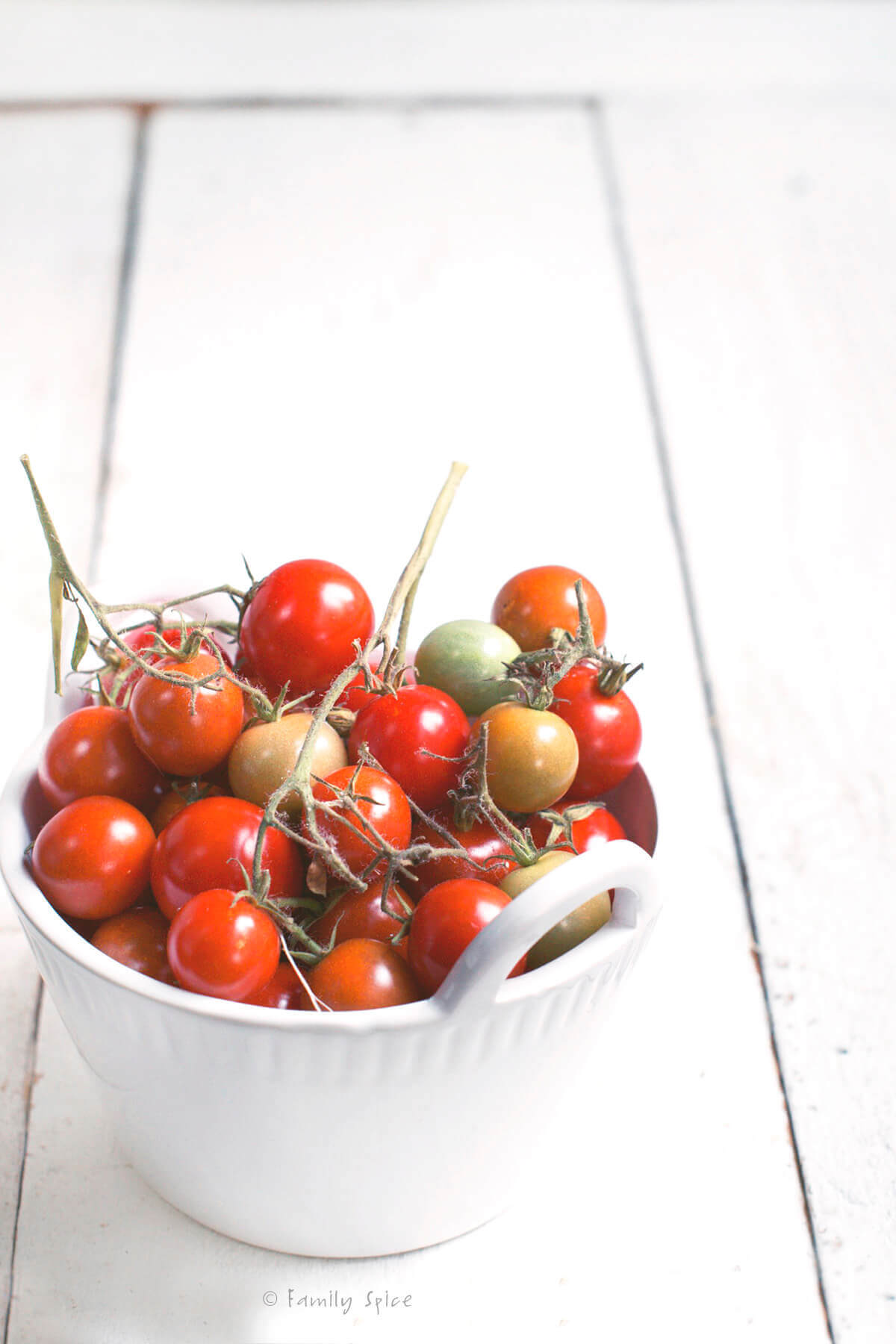 Cherry tomatoes in a white bowl on a white background