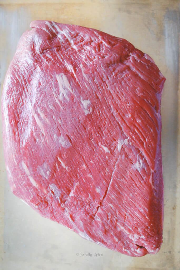 A large raw brisket on a stainless tray