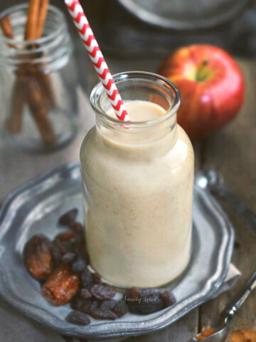 Closeup view of an old milk bottle with apple smoothie and a straw in it