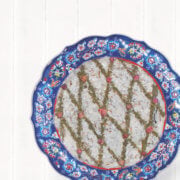 Top view of borani bademjan in a decorative bowl garnished with dried mint and rose petals.