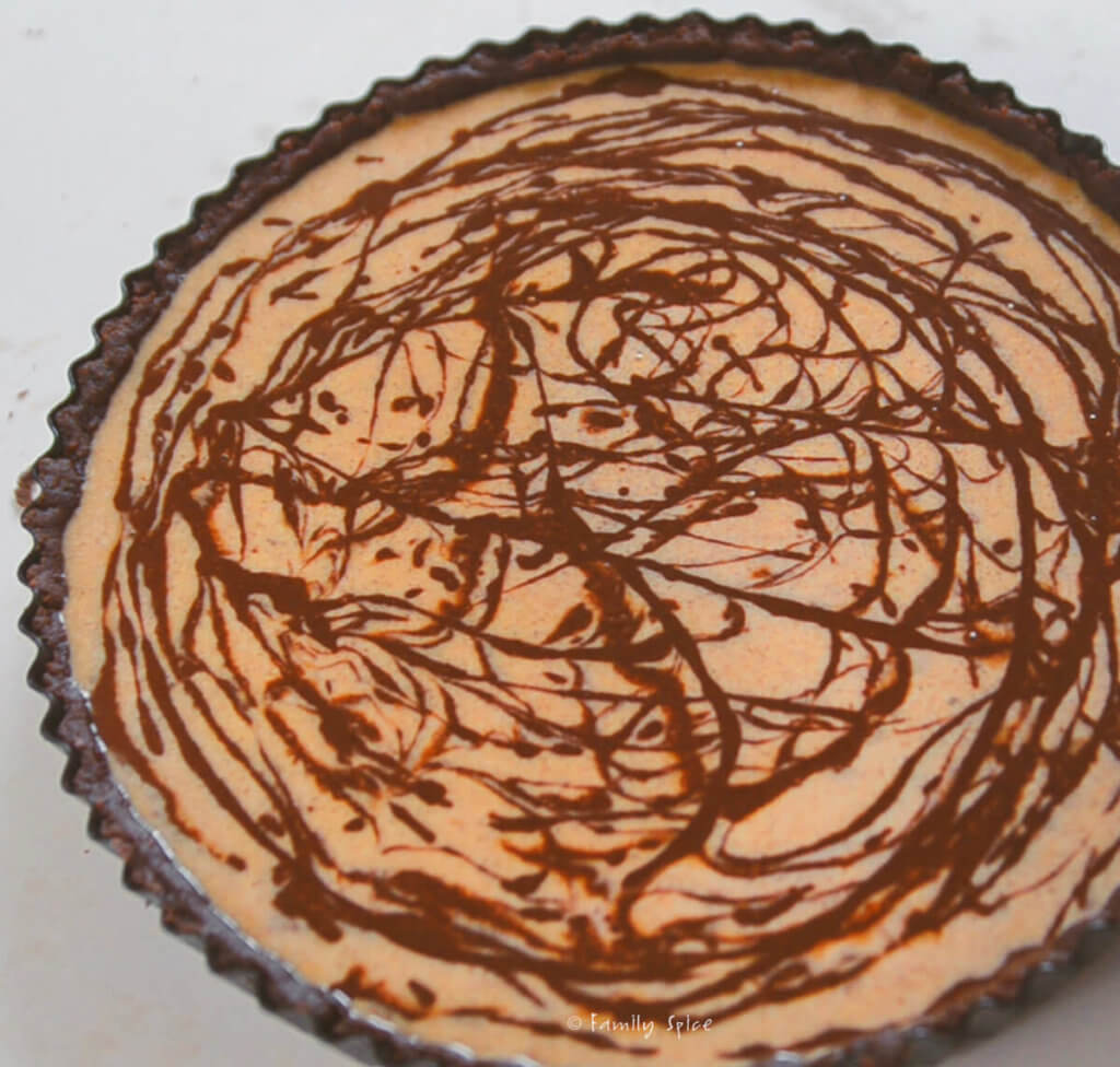 chocolate swirls inside pumpkin batter in a pie shell ready to bake