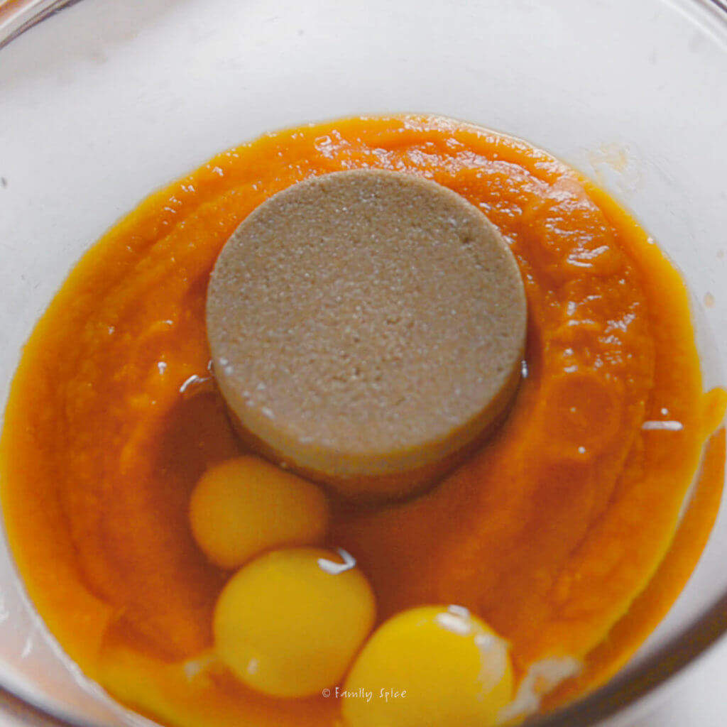 A glass bowl with pumpkin purée, brown sugar and eggs