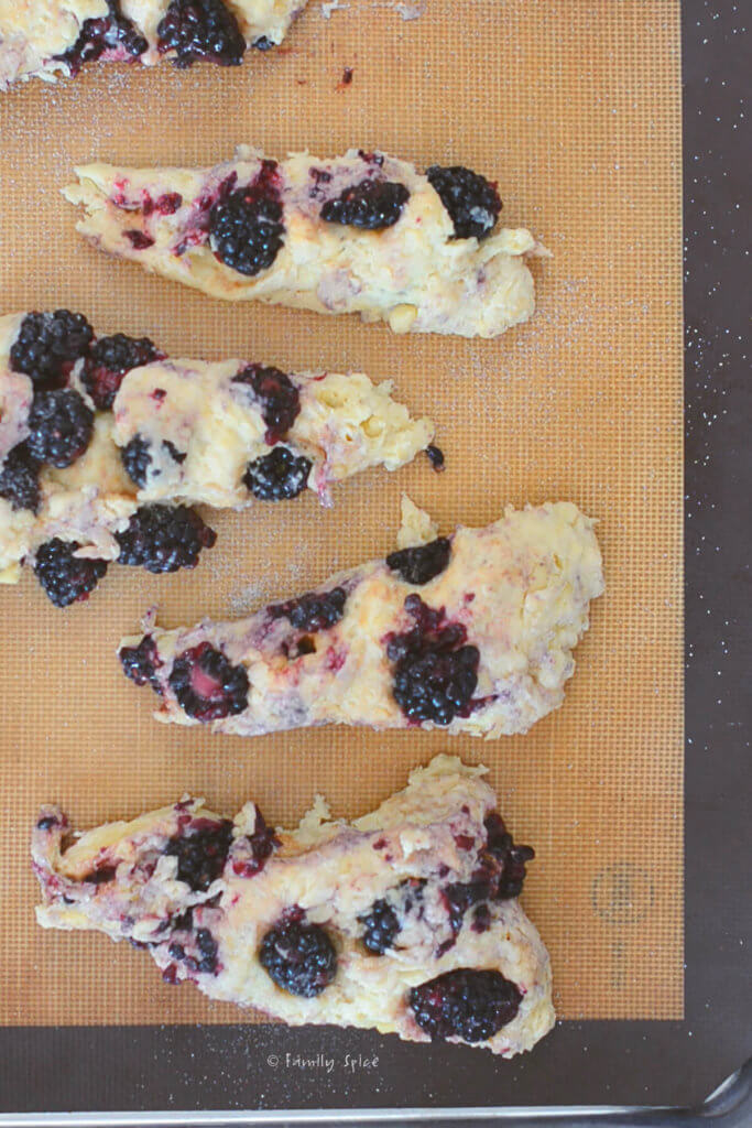 Blackberry scones on a silicone mat lined baking sheet ready to be baked