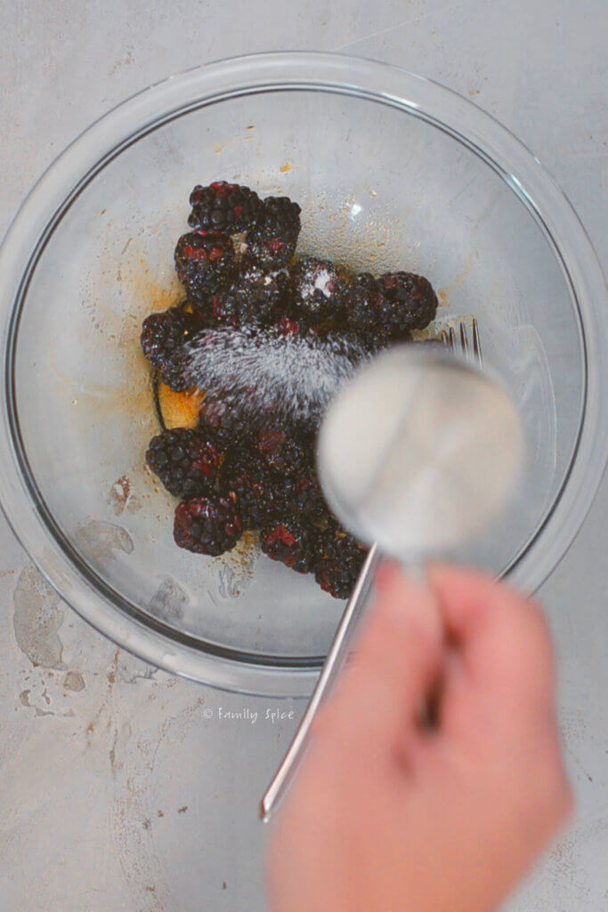 Adding sugar and balsamic vinegar to a bowl of blackberries