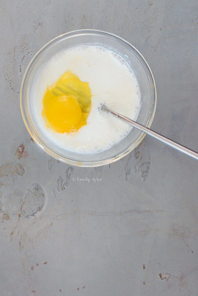 Mixing egg with yogurt and milk in a small glass bowl
