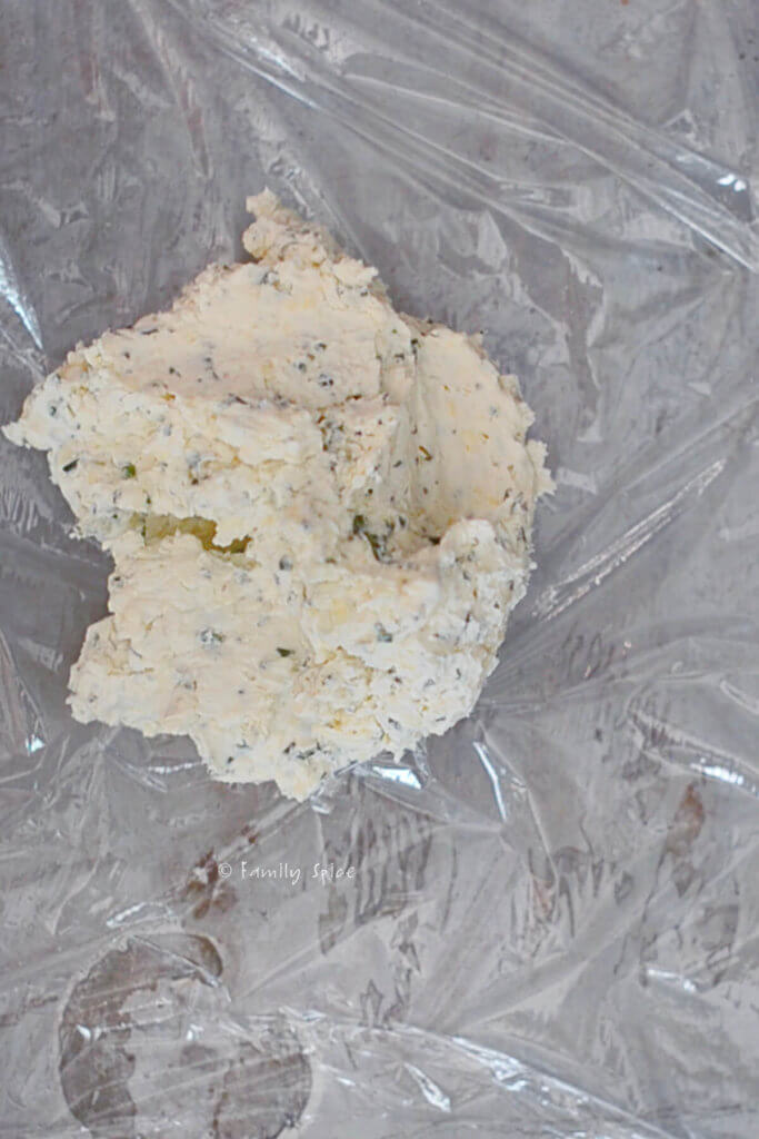 Garlic herb cheese mixture on a sheet of plastic wrap