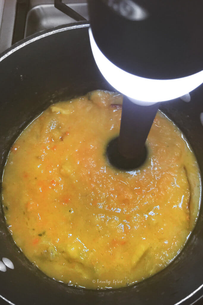 Immersion blender in a pot puréeing vegetables for soup