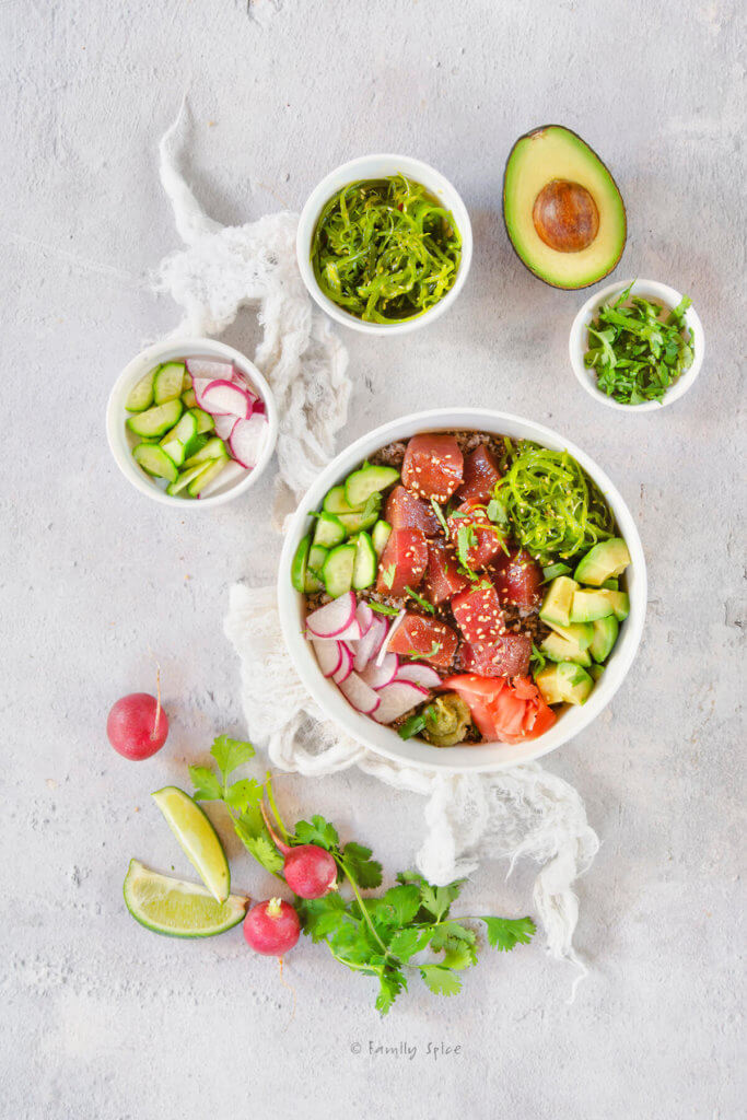 Top view of an ahi poke bowl with small bowls with other ingredients around it