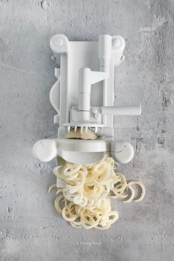 Overhead shot of a spiralizer and potatoes spiraled and on the counter