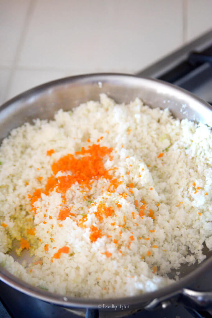 A small pan with cauliflower rice and grated turmeric root