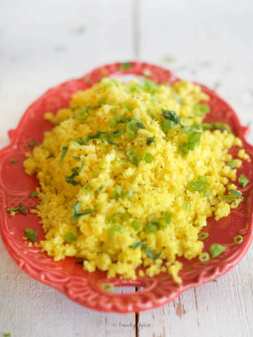 Closeup of a red oval platter with turmeric cauliflower rice