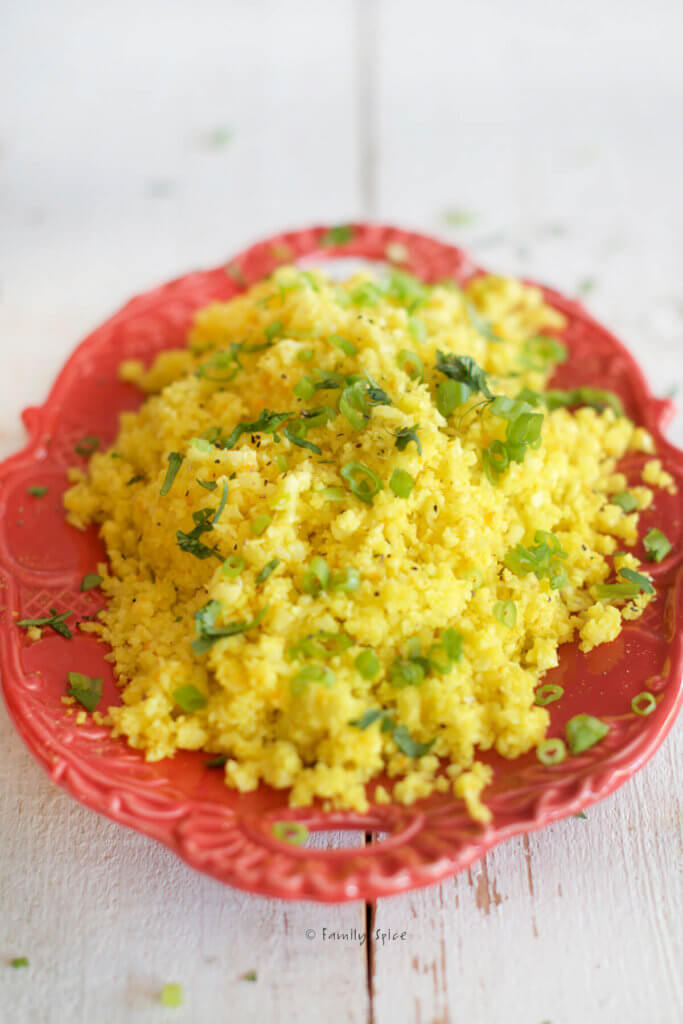 Closeup of a red oval platter with turmeric cauliflower rice