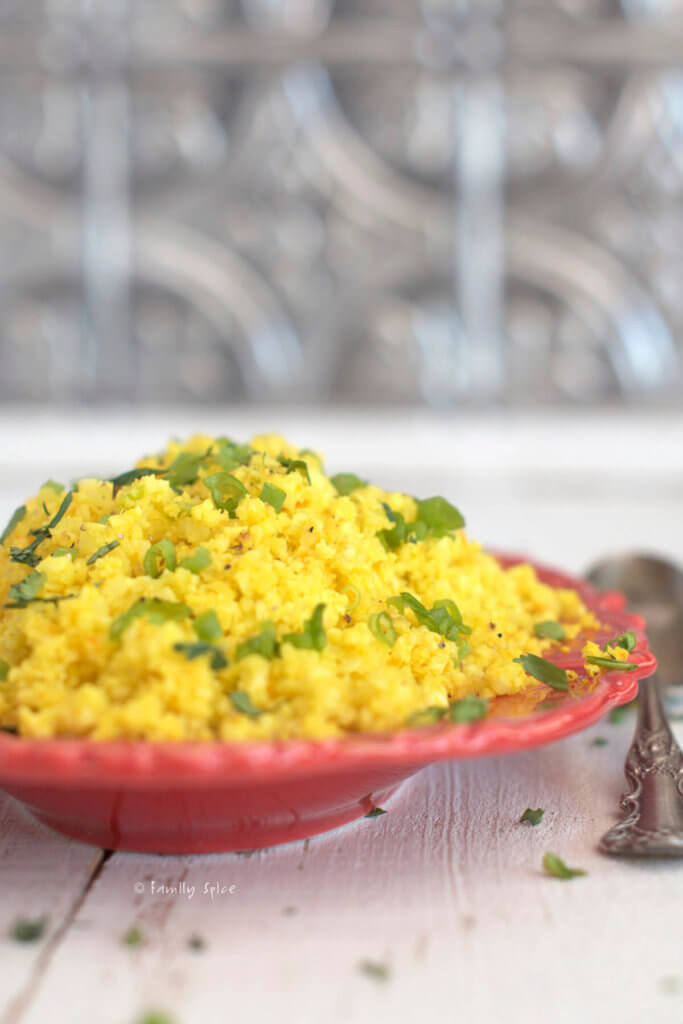 Side view of a red oval platter with turmeric cauliflower rice