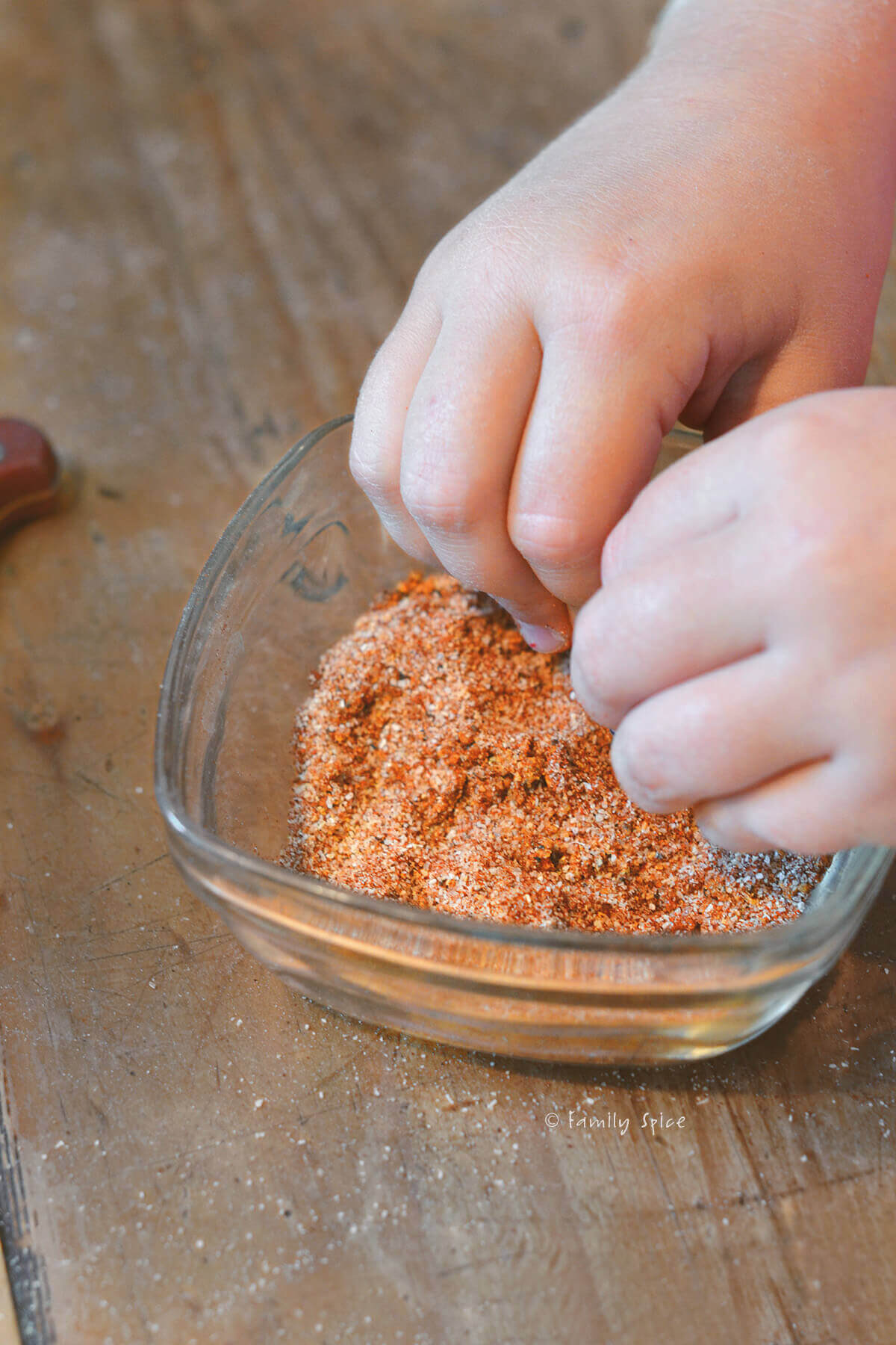 A child's hand mixing up seasonings