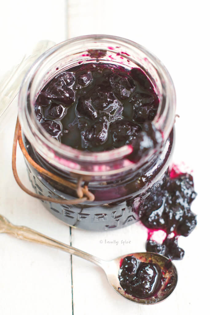 Closeup of an antique mason jar with blueberry honey jam with a spoon with jam next to it