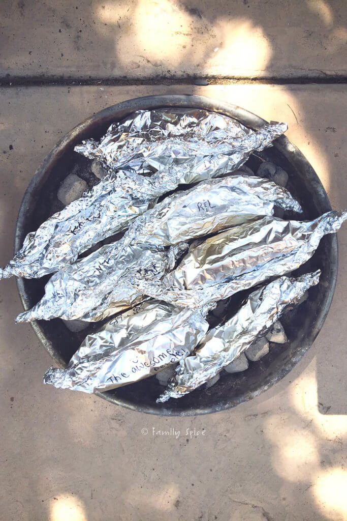 Rolls of foil wrapped potatoes over a campire