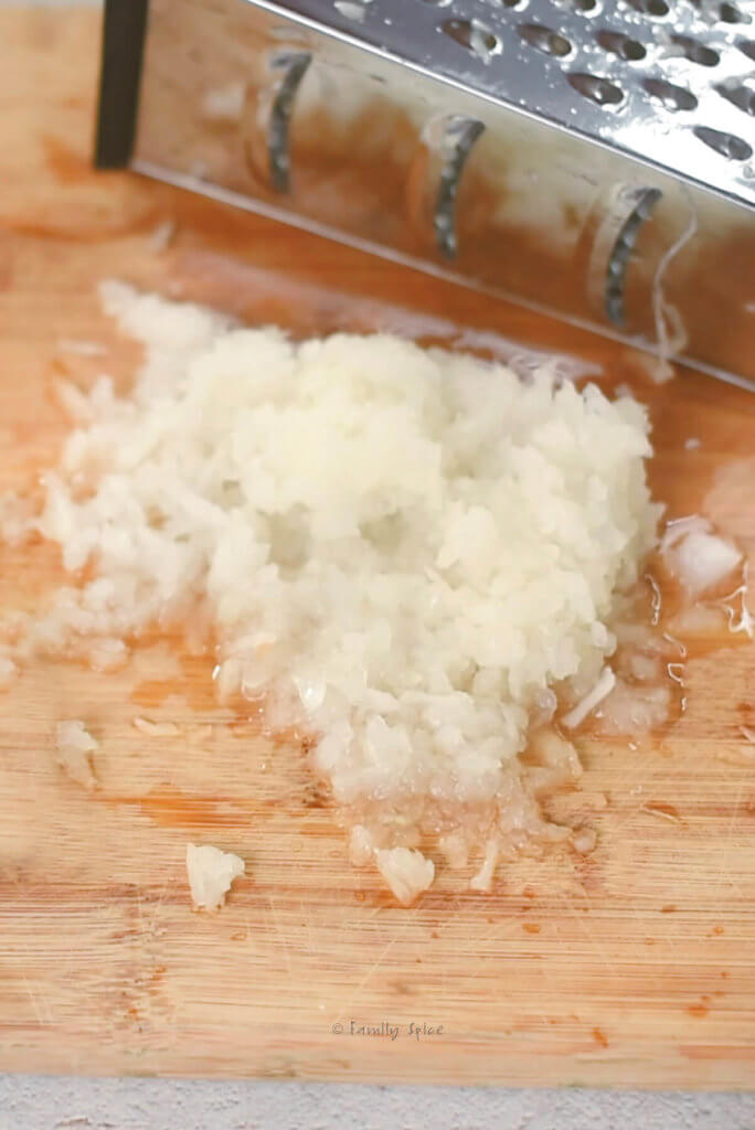 Grated onions on a wooden cutting board