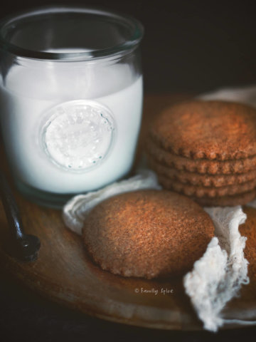 Closeup of quinoa spice cookies on a wood tray with a glass of milk