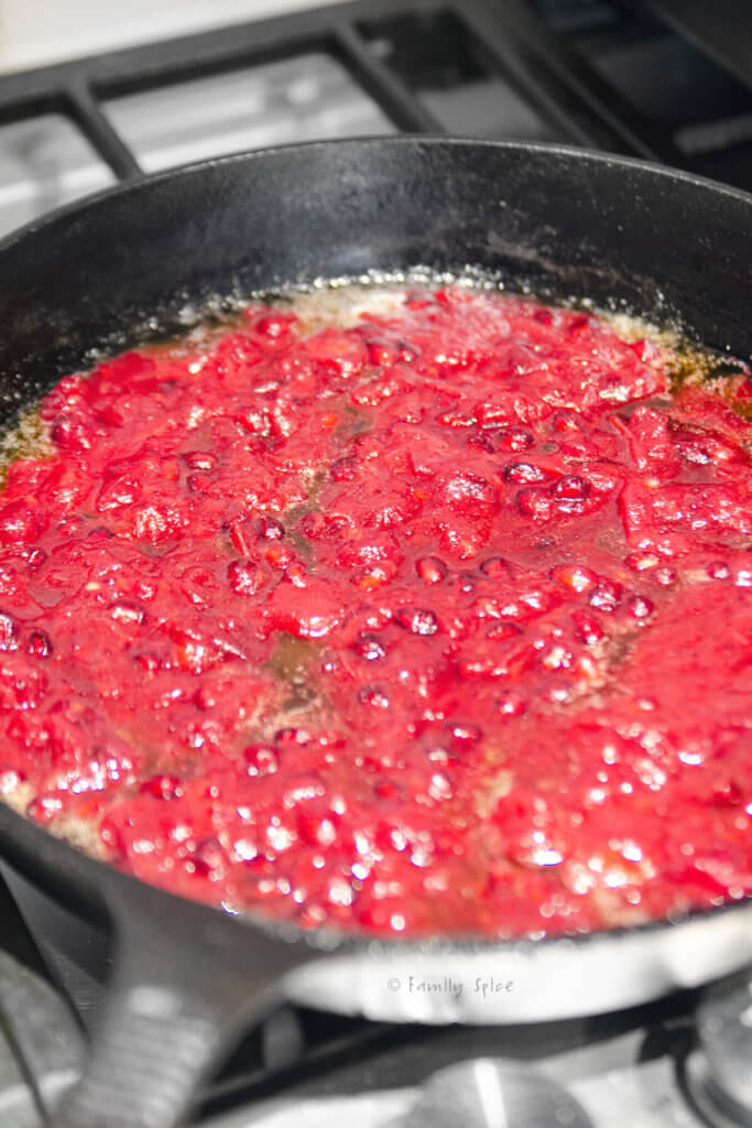 A cast iron skillet simmering cranberry sauce