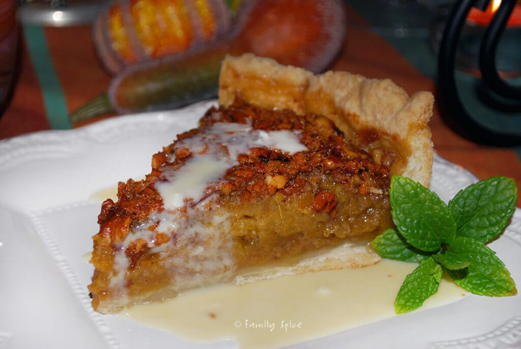 A slice of pecan pumpkin pie on a plate with whiskey butter