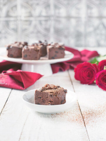 Closeup of Chocolate Rum Raisin Fudge on a White Cake Stand with Red Roses