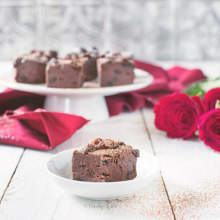 Closeup of Chocolate Rum Raisin Fudge on a White Cake Stand with Red Roses