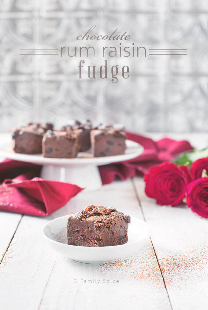 Closeup of Chocolate Rum Raisin Fudge on a White Cake Stand with Red Roses by FamilySpice.com