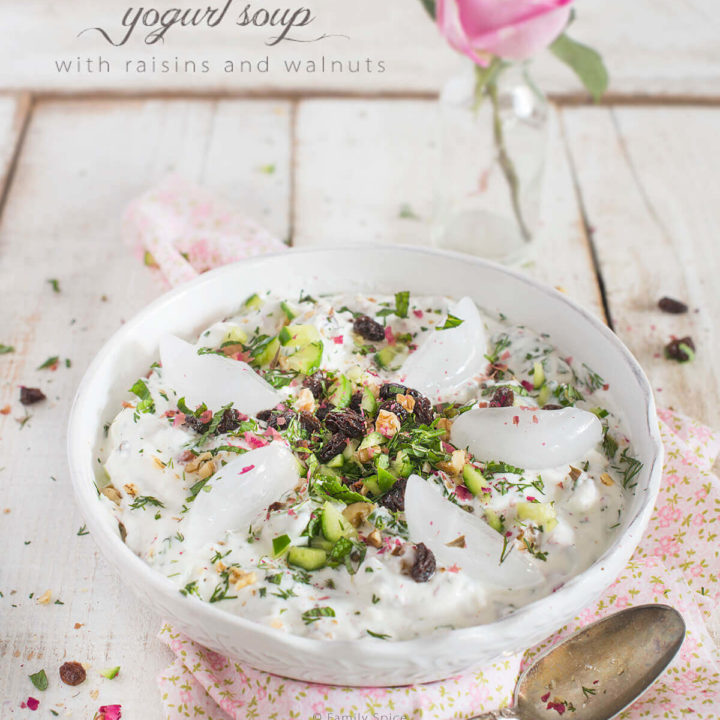 A bowl of Persian cold yogurt soup topped with rose petals, herbs and ice cubes by FamilySpice.com