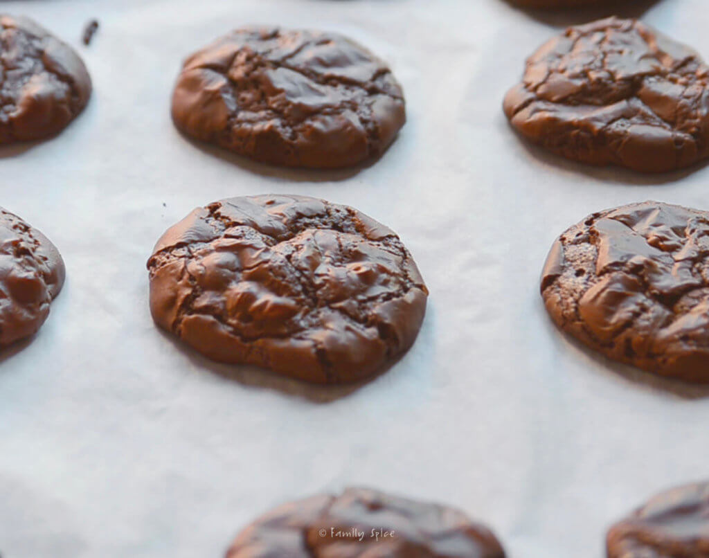 Freshly baked brownie cookies cooling on a baking sheet lined with parchment paper